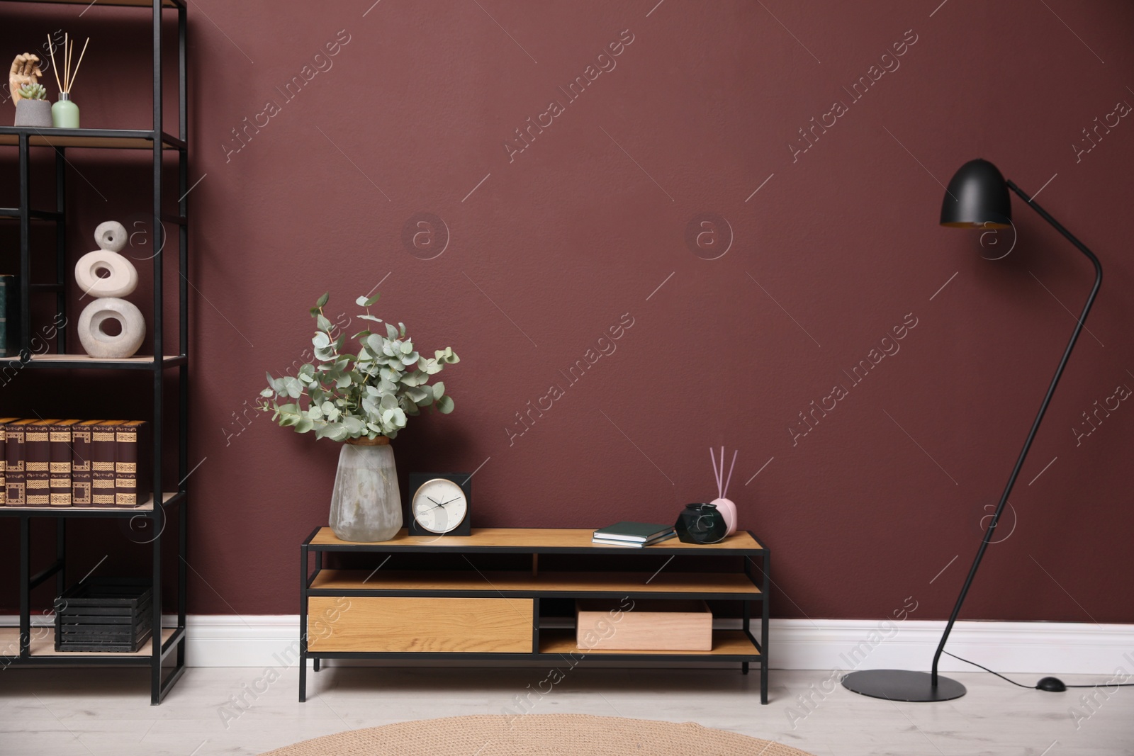 Photo of Elegant room interior with wooden cabinet, shelving unit and floor lamp near brown wall