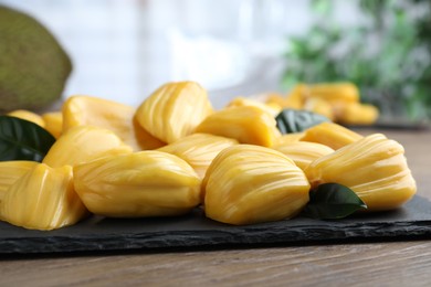 Fresh exotic jackfruit bulbs on wooden table, closeup