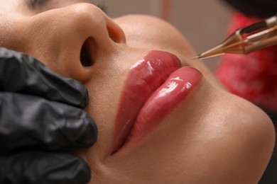 Photo of Young woman undergoing procedure of permanent lip makeup in tattoo salon, closeup