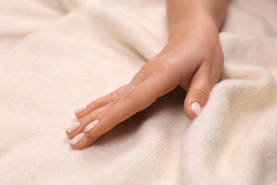 Photo of Woman touching soft beige knitted fabric, closeup
