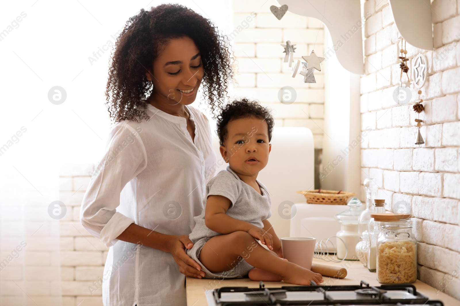 Photo of African-American woman with her baby in kitchen. Happiness of motherhood