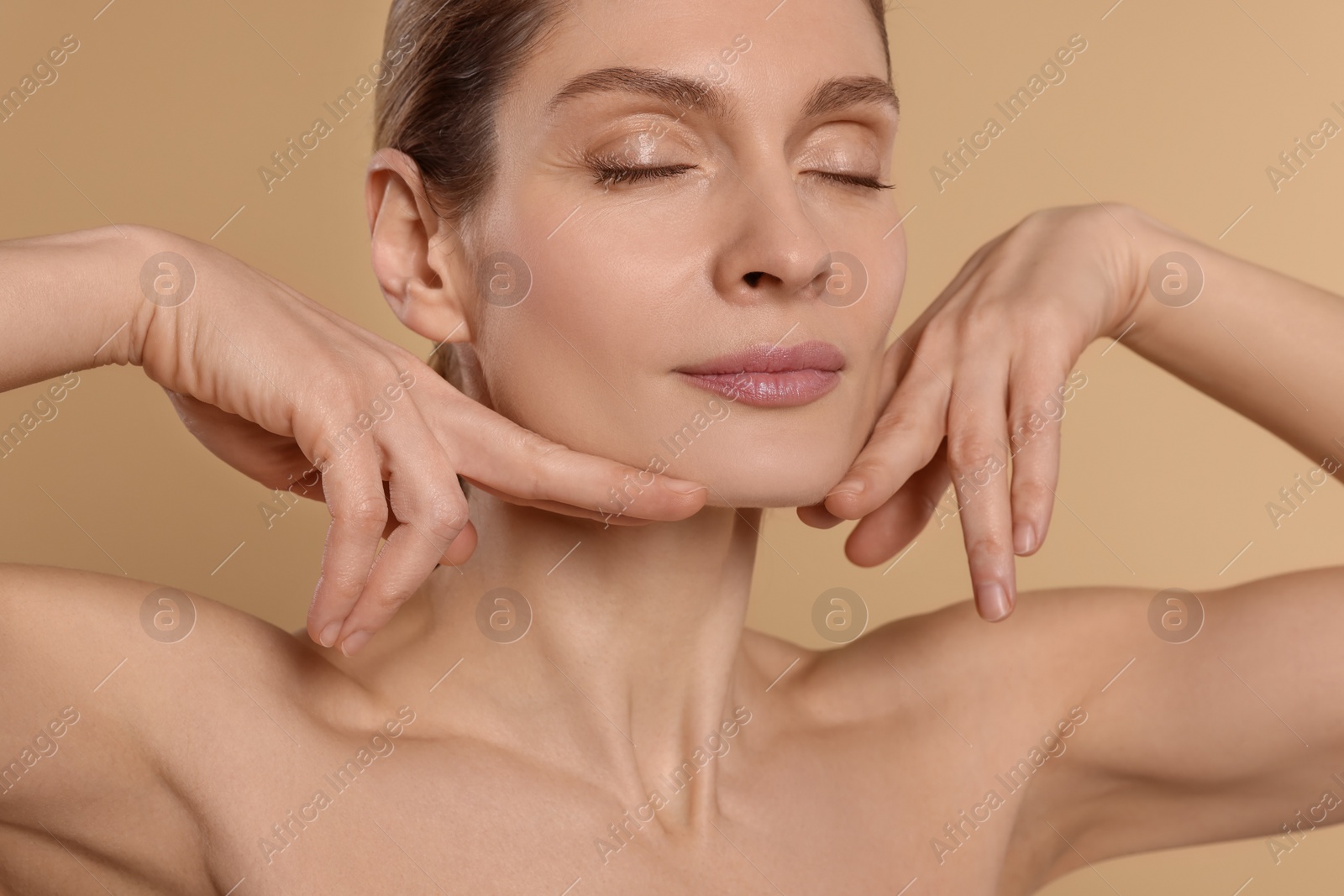 Photo of Woman massaging her face on beige background