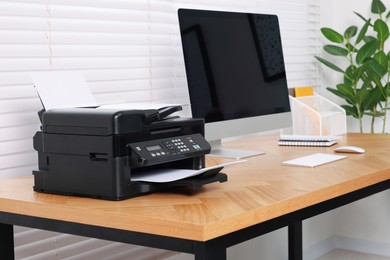 Photo of Modern printer with paper on wooden desk indoors