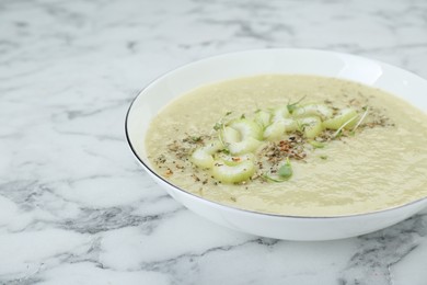 Bowl of delicious celery soup on white marble table, closeup