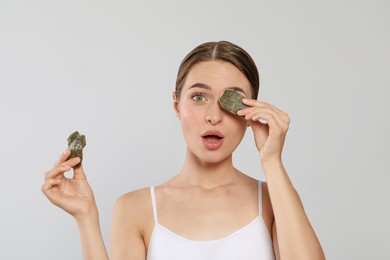Photo of Young woman with green tea bags on white background. Eye skin care