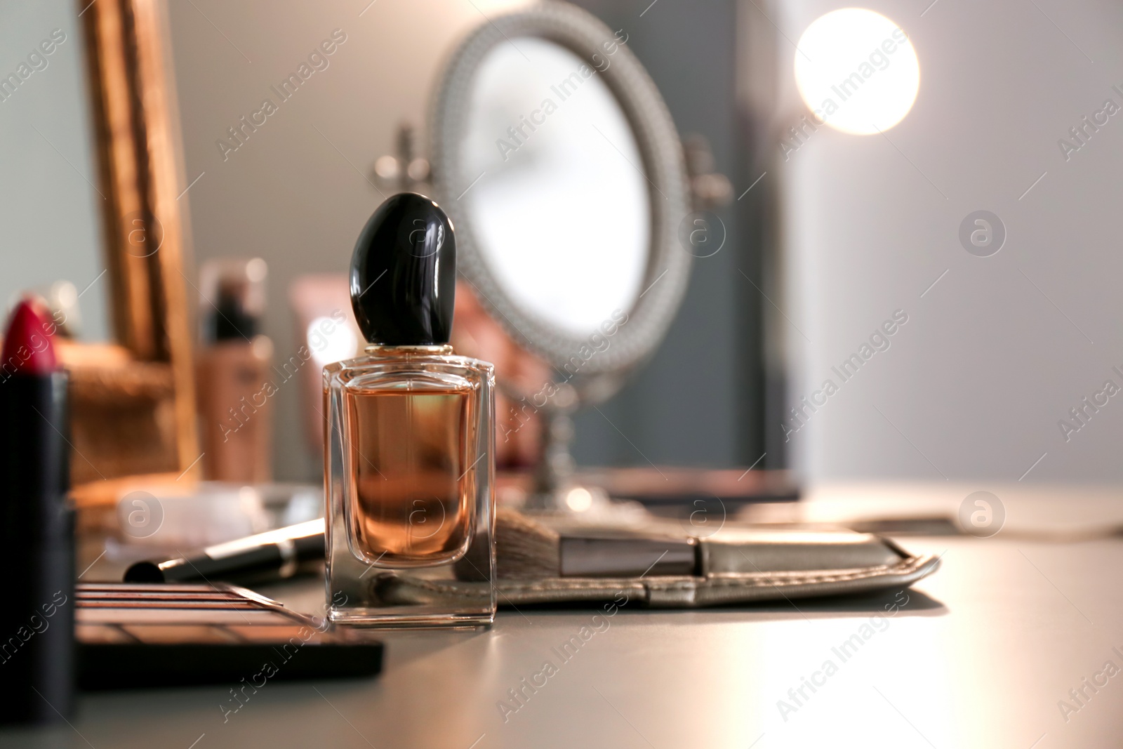 Photo of Bottle of perfume and makeup products on dressing table