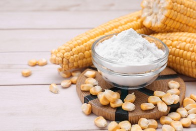 Photo of Bowl with corn starch, ripe cobs and kernels on wooden table. Space for text