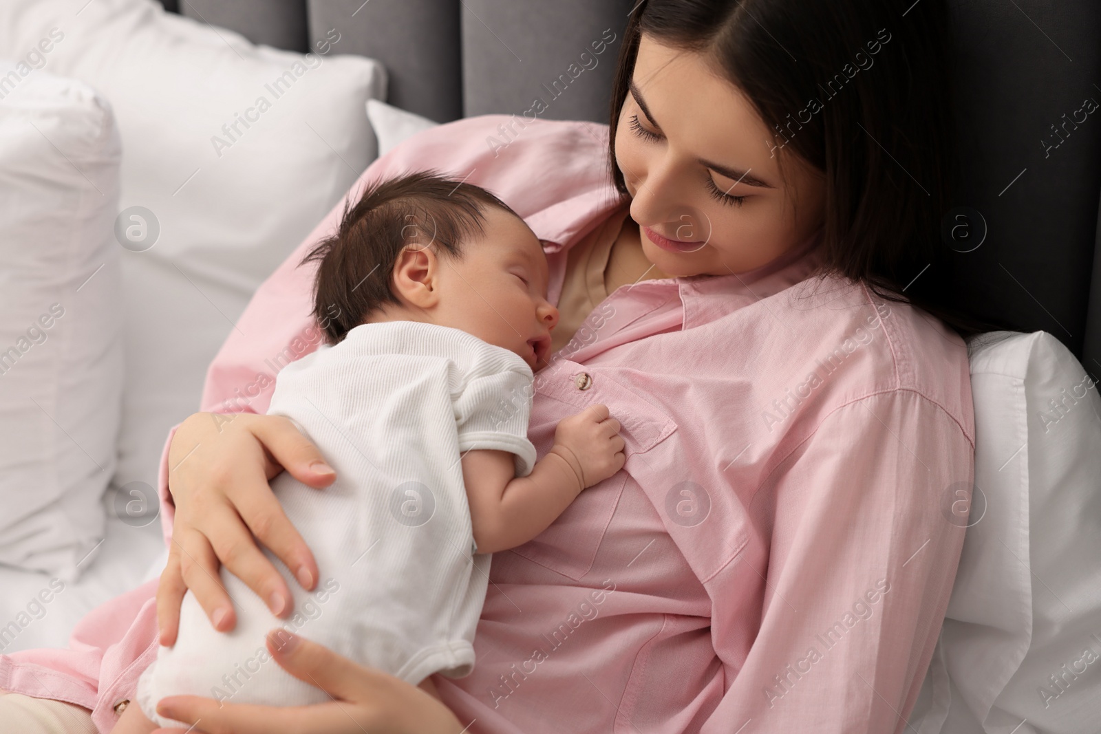 Photo of Mother with her sleeping newborn baby in bed