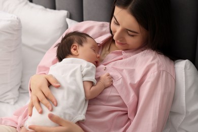 Mother with her sleeping newborn baby in bed