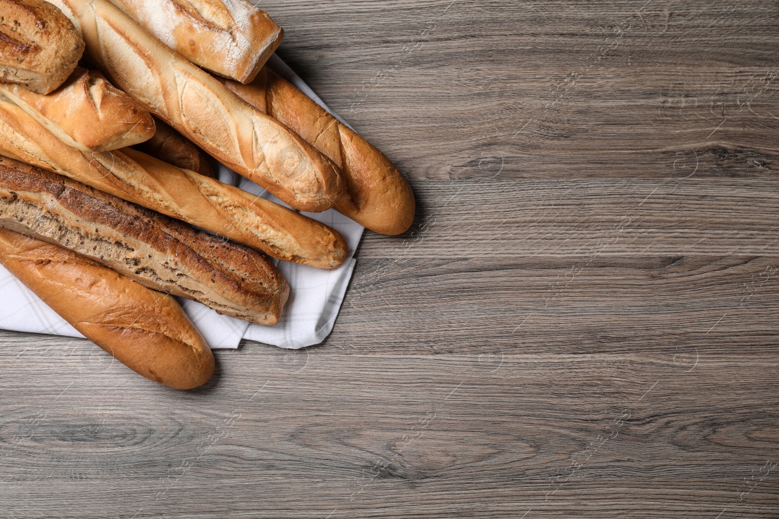 Photo of Different tasty baguettes on wooden table, flat lay. Space for text