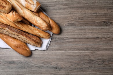 Photo of Different tasty baguettes on wooden table, flat lay. Space for text