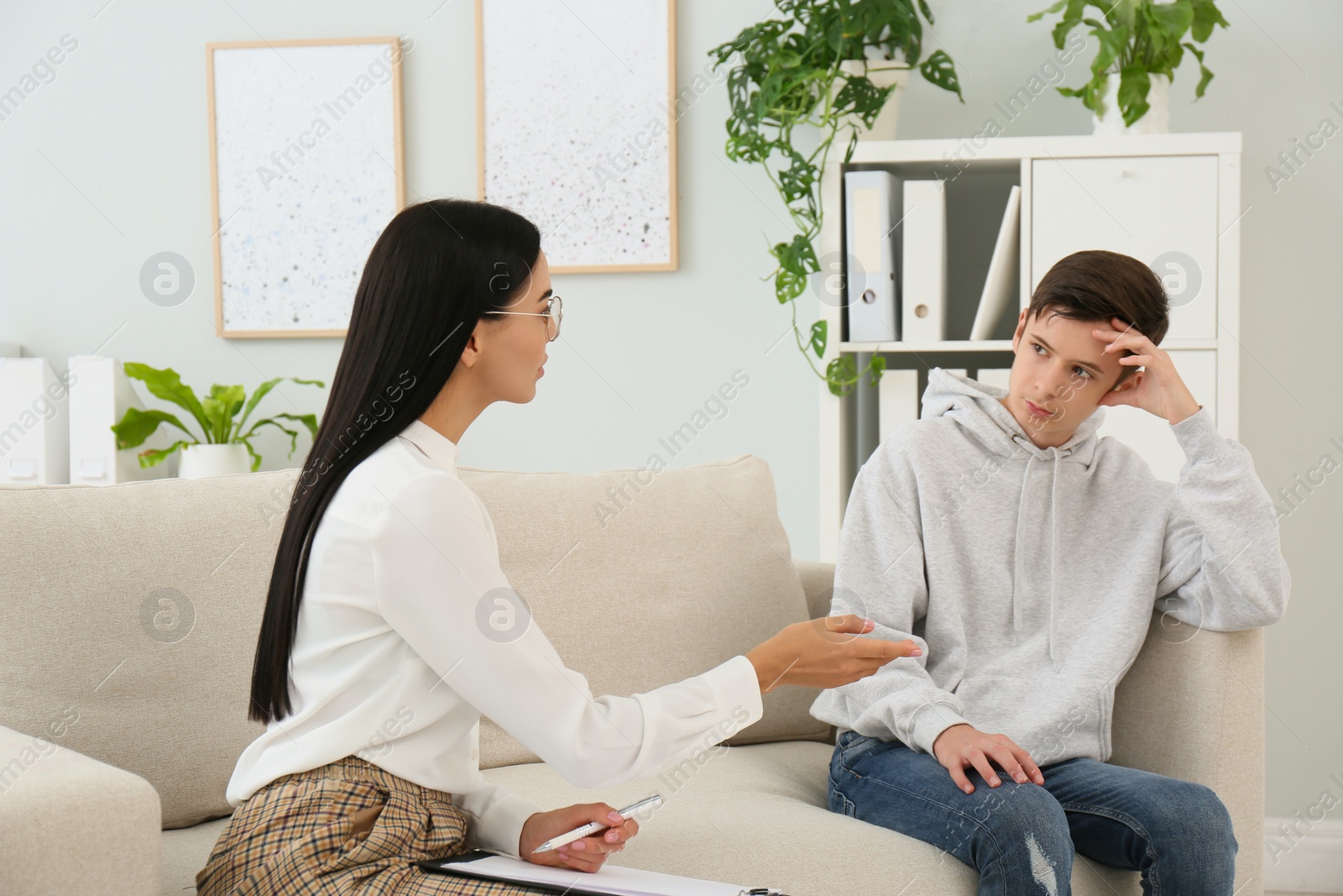 Photo of Young psychologist working with teenage boy in office