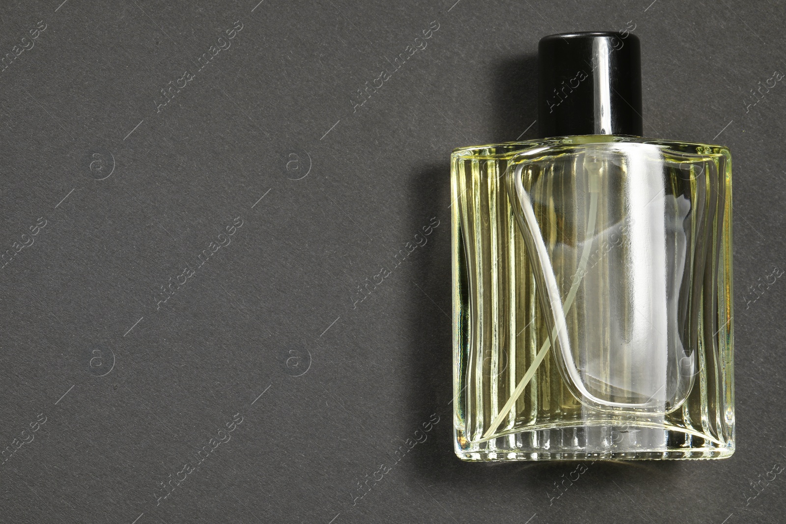 Photo of Luxury men`s perfume in bottle on black background, top view. Space for text