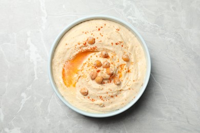 Photo of Tasty hummus with garnish in bowl on light grey marble table, top view