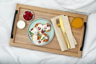 Photo of Delicious cottage cheese pancakes with fresh raspberries, mint, sour cream and icing sugar served on wooden tray, top view