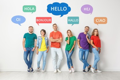 Image of Happy people posing near light wall and illustration of speech bubbles with word Hello written in different languages