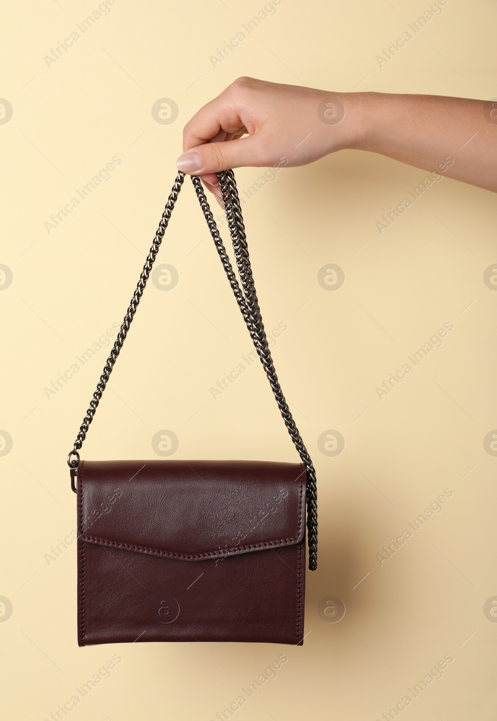 Photo of Woman holding stylish bag on beige background, closeup