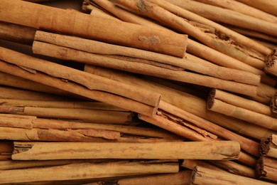 Photo of Aromatic cinnamon sticks as background, top view