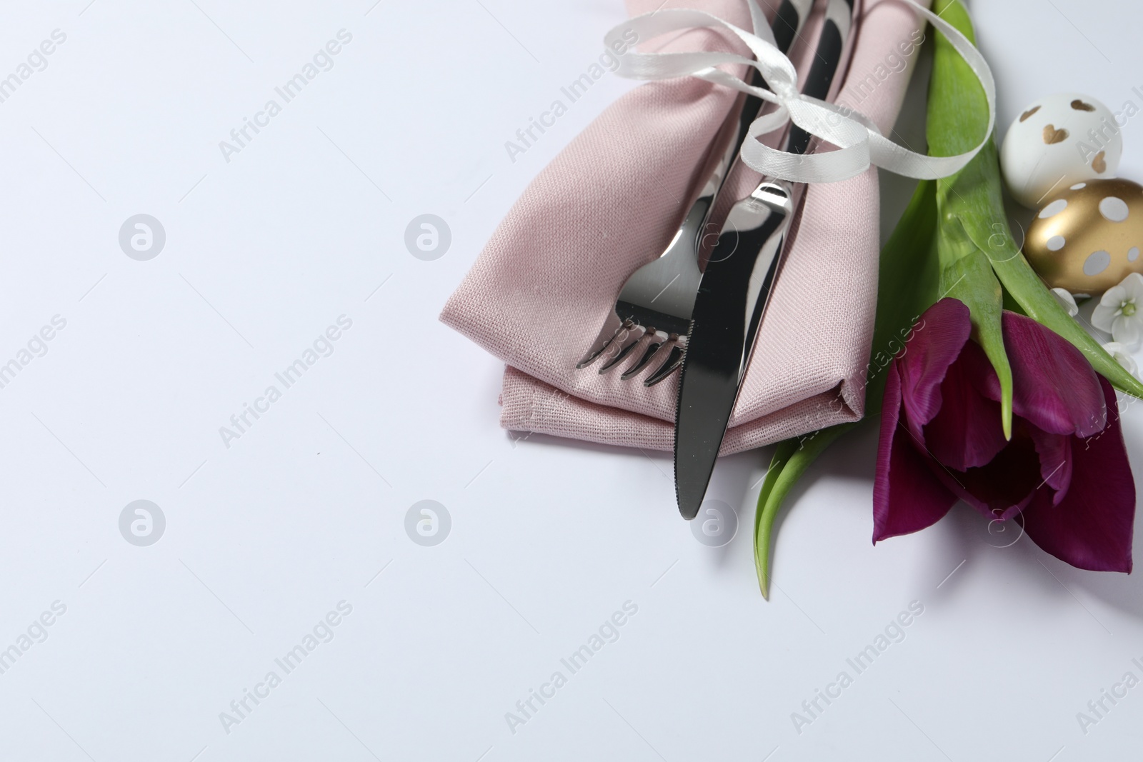 Photo of Cutlery set, Easter eggs and tulip on white background, space for text. Festive table setting