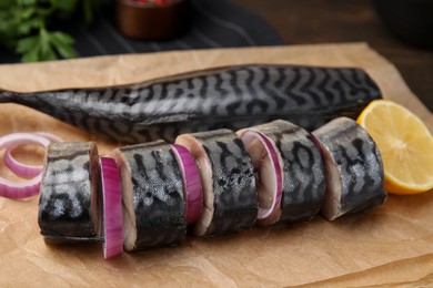 Photo of Tasty salted mackerel, onion and lemon on parchment, closeup