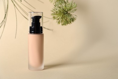 Bottle of skin foundation on beige background, space for text. Makeup product