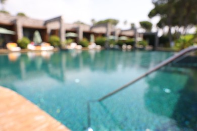 Photo of Luxury resort with outdoor swimming pool on sunny day, blurred view