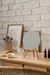 Photo of Mirror, makeup products, perfume and jewelry on wooden dressing table