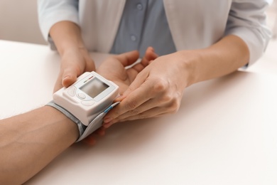 Doctor checking patient's blood pressure in hospital, closeup. Cardiology concept