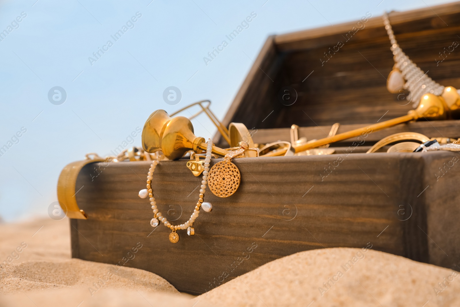 Photo of Open wooden treasure chest on sandy beach, closeup