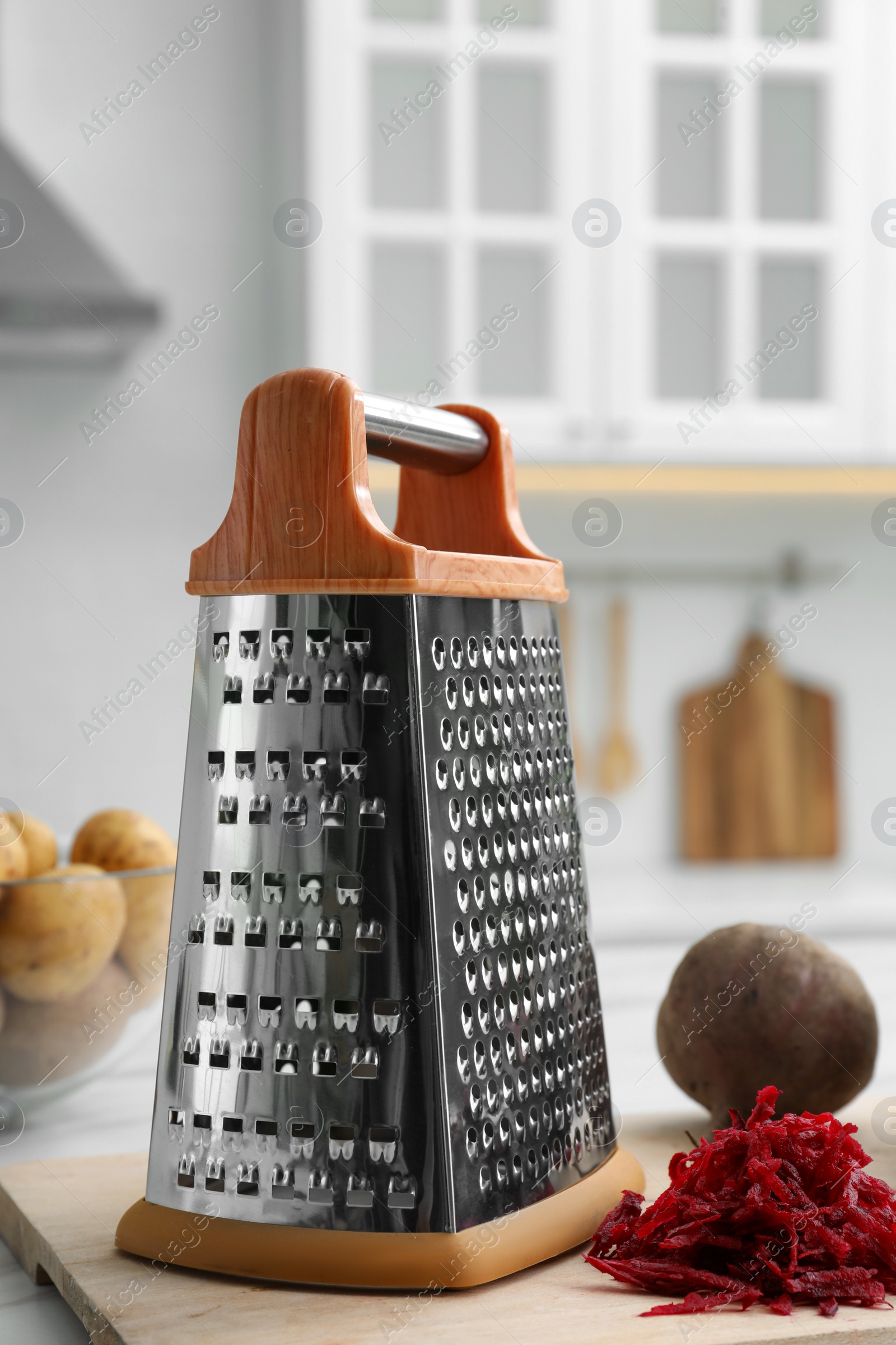 Photo of Grater and fresh ripe beetroot on table in kitchen