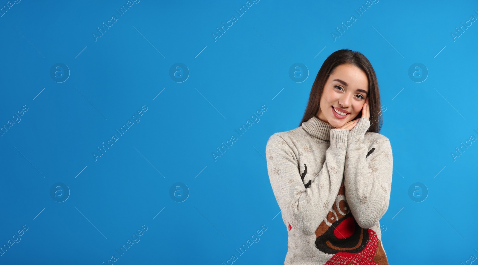 Photo of Young woman in Christmas sweater on blue background, space for text