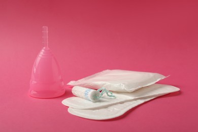 Photo of Menstrual cup, pads and tampon on pink background