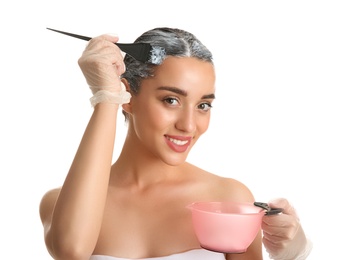 Young woman dyeing her hair against white background