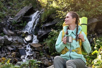 Photo of Tourist with cup near waterfall in mountains. Space for text