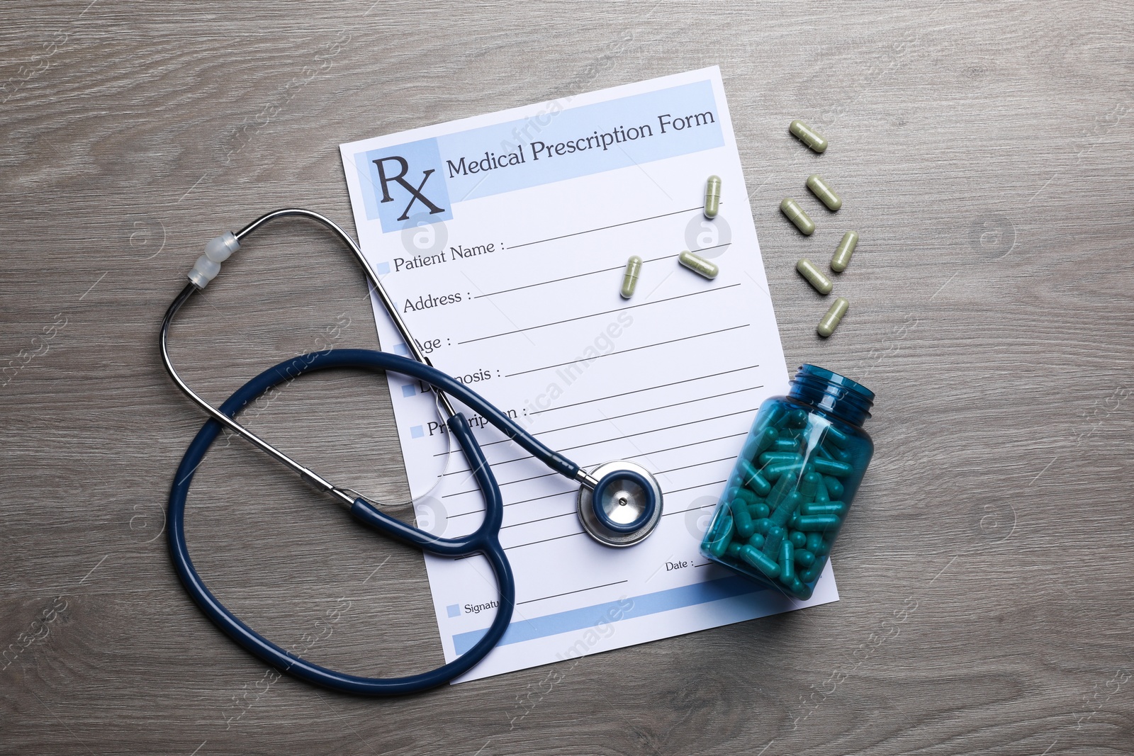 Photo of Medical prescription form, stethoscope and pills on wooden table, flat lay