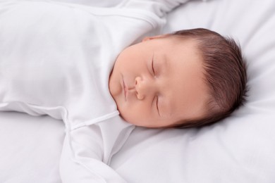 Cute newborn baby sleeping on white blanket, top view