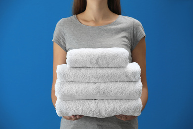 Woman holding fresh towels on blue background, closeup