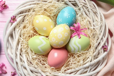 Photo of Wicker nest with colorful painted Easter eggs, top view