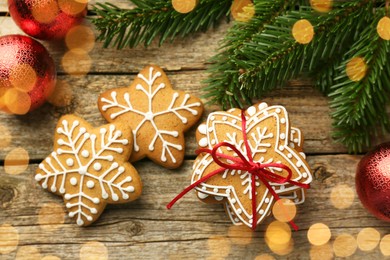 Photo of Tasty Christmas cookies with icing and festive decor on wooden table, flat lay