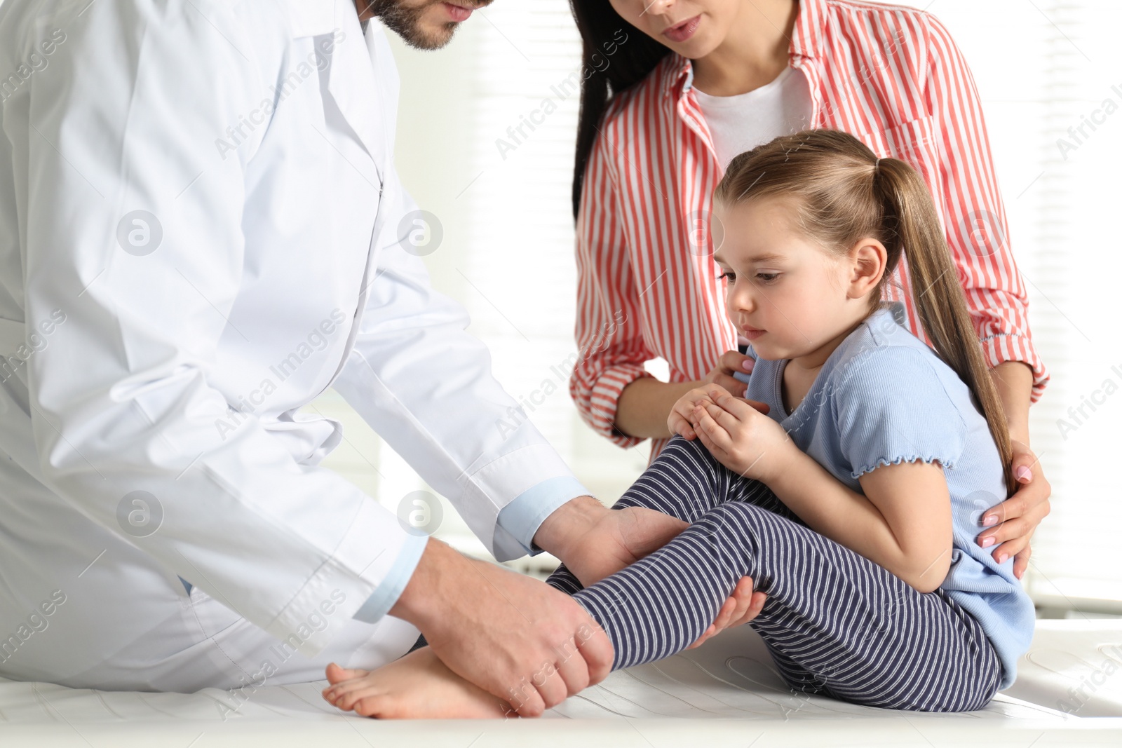 Photo of Professional orthopedist examining little patient's leg in clinic