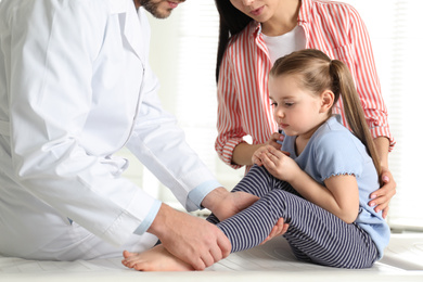 Photo of Professional orthopedist examining little patient's leg in clinic