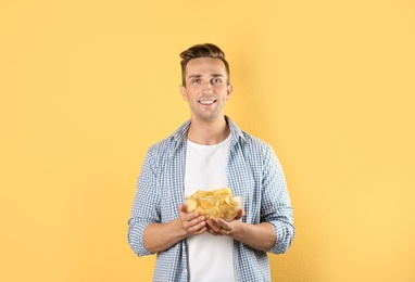 Photo of Man with bowl of potato chips on color background