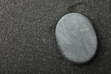 Presentation of product. Stone podium on black sand, top view. Space for text