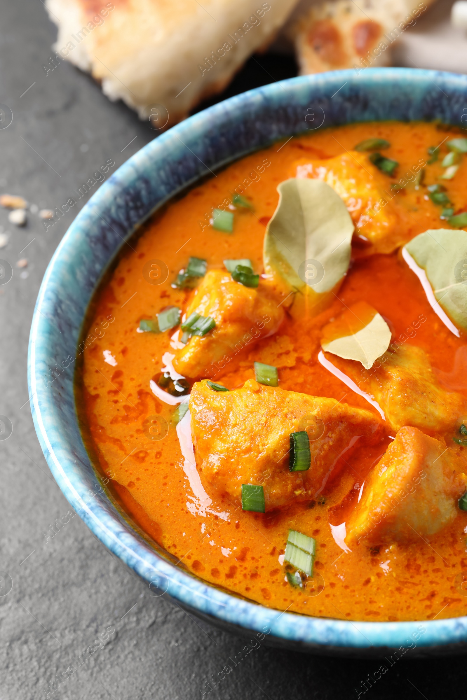 Photo of Bowl of delicious chicken curry on black table, closeup