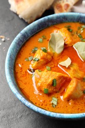 Bowl of delicious chicken curry on black table, closeup