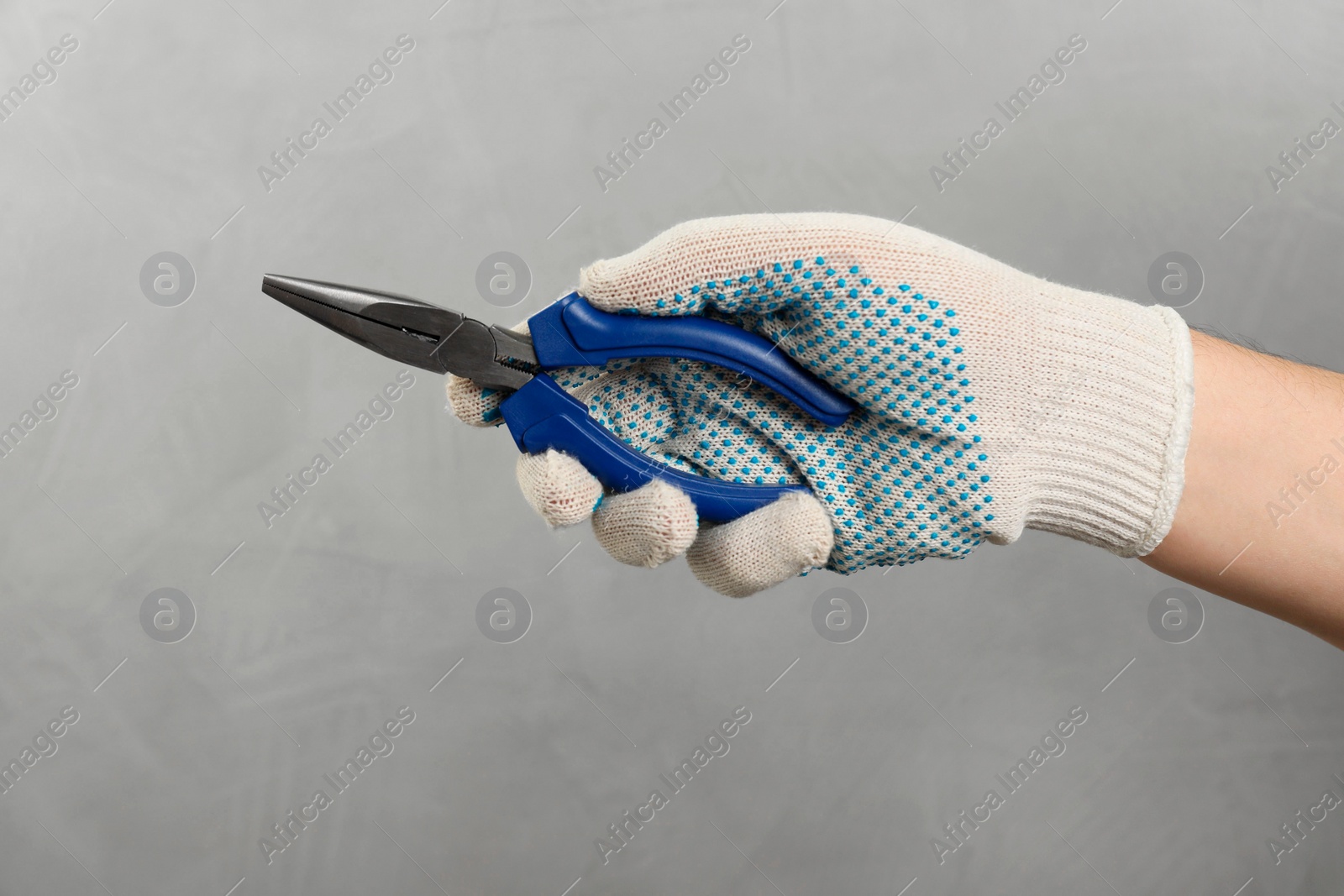 Photo of Man with needle nose pliers on grey background, closeup