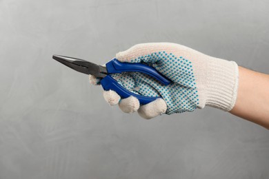 Photo of Man with needle nose pliers on grey background, closeup