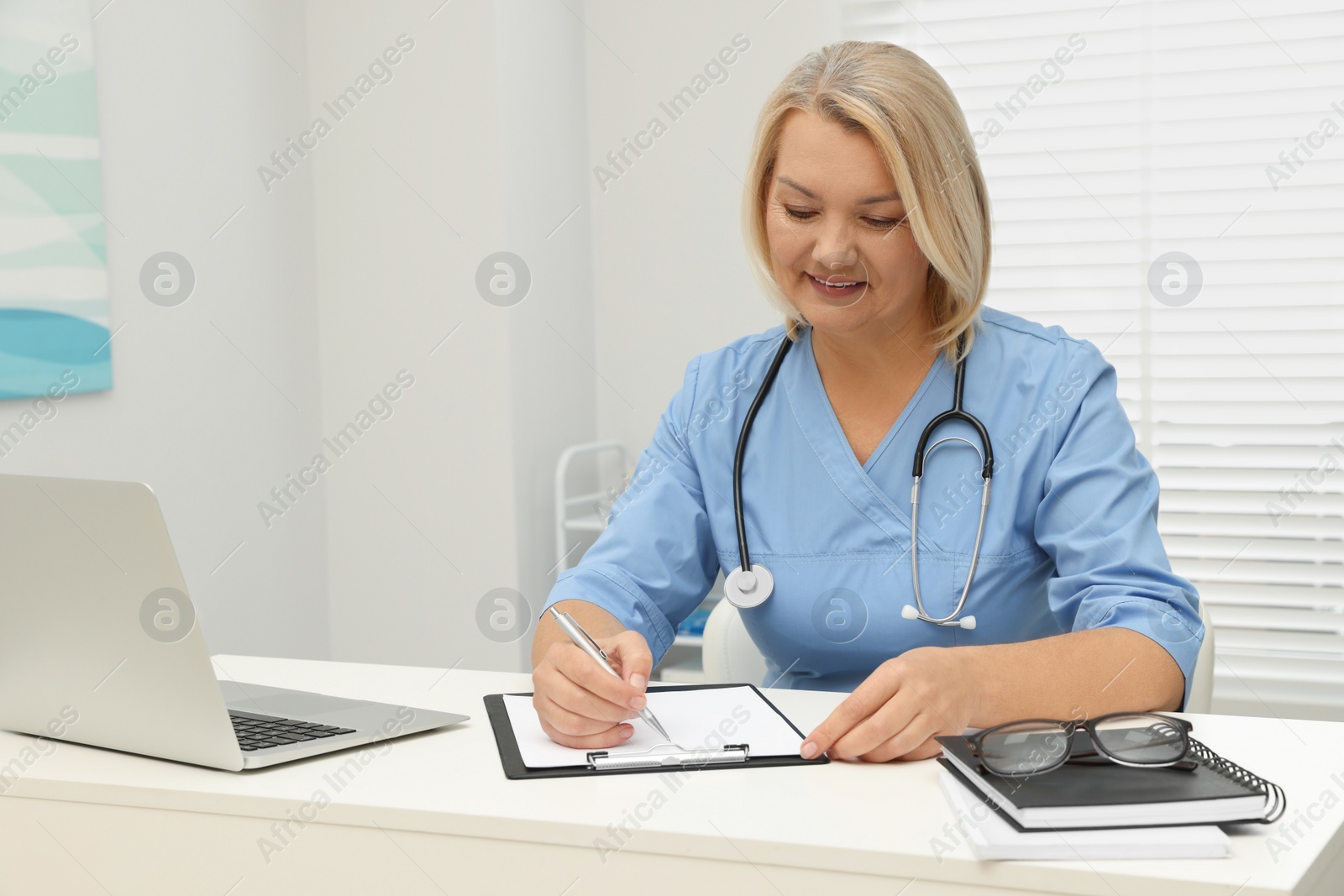 Photo of Doctor writing at white table in clinic