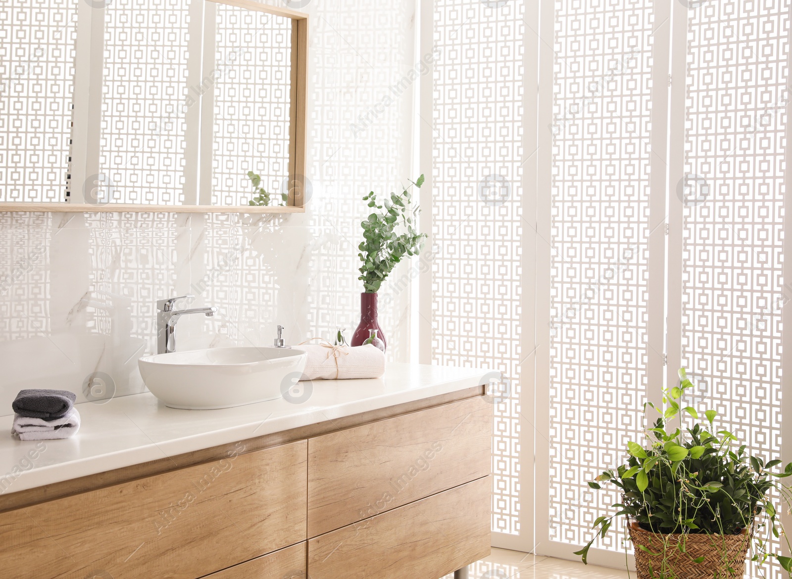 Photo of Stylish bathroom interior with countertop, mirror and plants. Design idea