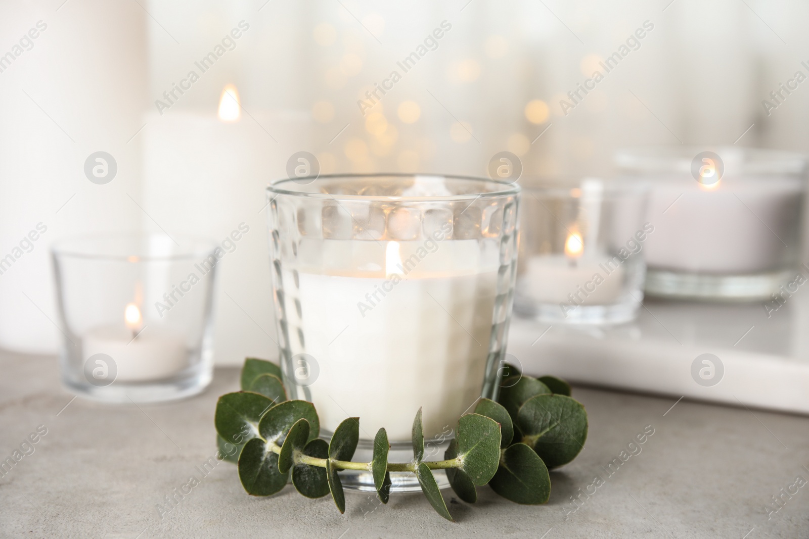 Photo of Burning aromatic candle and eucalyptus branch on table